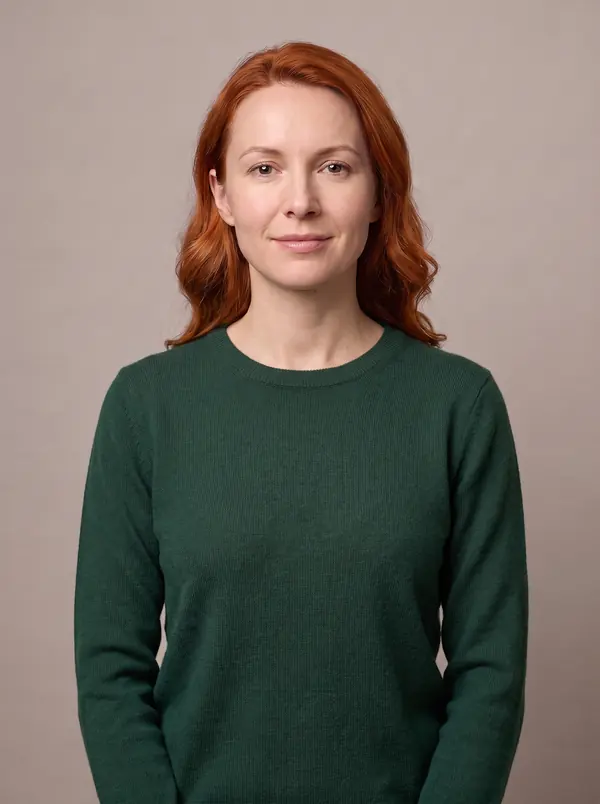Woman with copper red hair wearing a forest green crew-neck sweater
