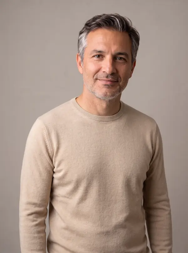 The same man with salt-and-pepper hair wearing a sand beige crew-neck sweater